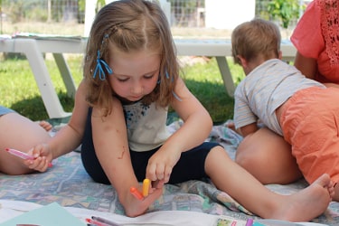 Групповое занятие арт-терапией: дети увлеченно рисуют и развивают творческие навыки на открытом воздухе в Полихроно